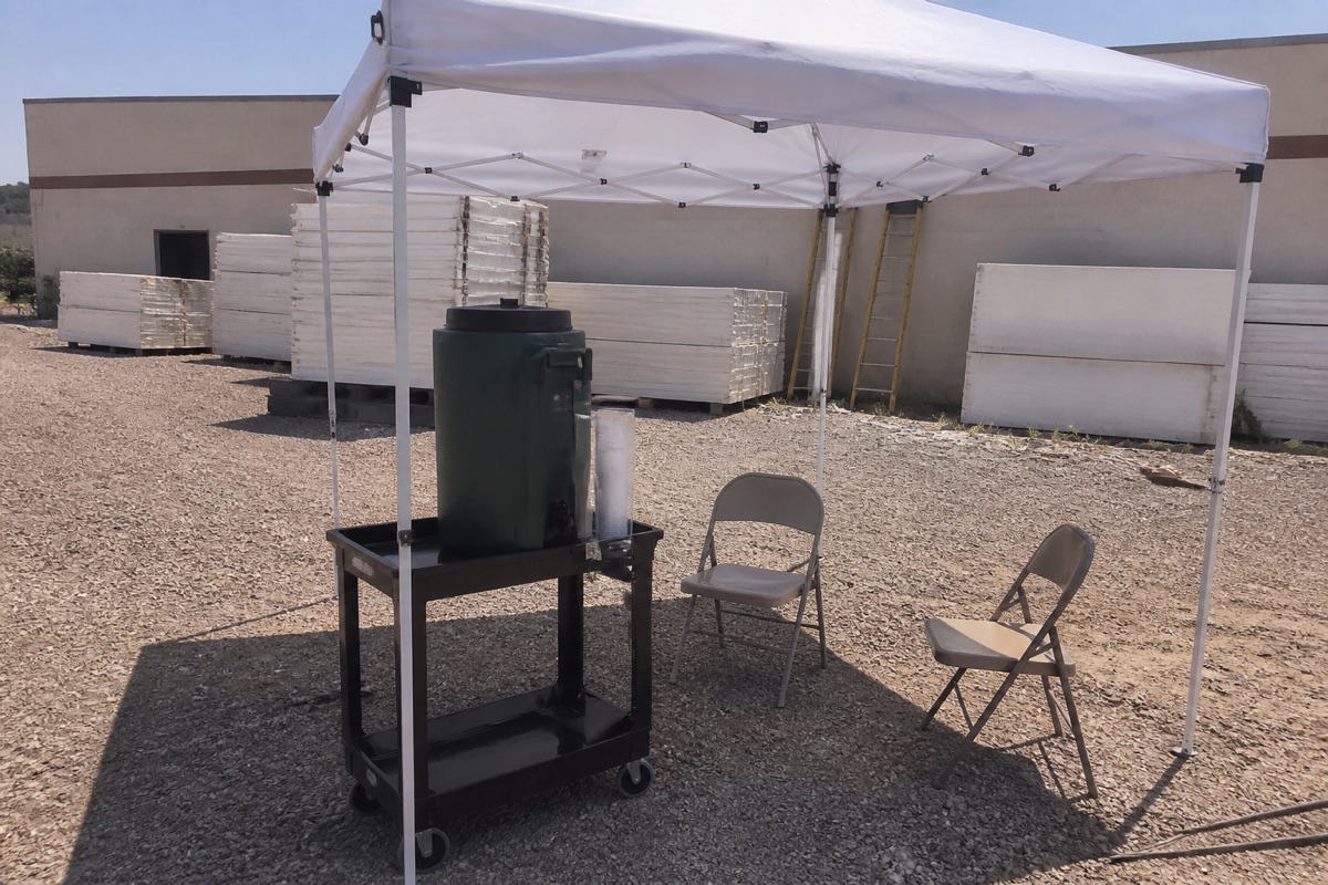 Dispensador verde bajo un toldo blanco, mié 07-15 06:35